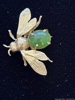Front view of gold insect brooch with green nephrite body