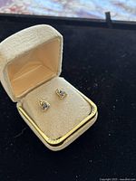 Pair of sapphire knot earrings displayed in cream fabric box