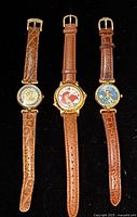 Front view of the three Ariel watches showing dial artwork and straps
