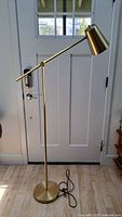 Full view of brass adjustable floor lamp with base and cord