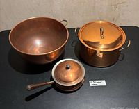 Copper stock pot with lid, saucepan with lid, large bowl—group front view