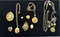 Front view of all lockets and charm necklace in tray