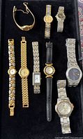 Front view of nine assorted wristwatches on black tray
