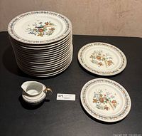 Stack of dinner plates, individual luncheon and bread plates, and creamer displayed
