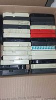 Box of multiple 8 track tapes stacked, showing various colors and some wear.