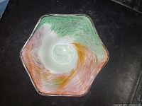 Top view of a hexagonal glass dish with multicolored swirl pattern in green, white, orange, and pink.