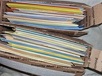 Two cardboard boxes filled with a large quantity of assorted greeting cards and envelopes of various colors and sizes.