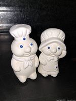 Front view of both Pillsbury Doughboy ceramic salt and pepper shakers showing detailed facial features and clothing.