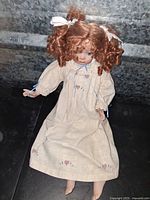 Full doll showing curly red hair, cream dress with heart motifs, seated position