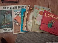 Photo showing the full set of 8 vintage children's books with visible titles and cover illustrations, placed on wooden floor.