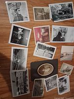 Top-down photo showing various black and white vintage photos laid out on wooden surface, including portraits, outdoor groups, and scenic shots.