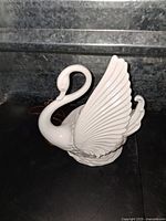 Front side view of white ceramic swan lamp showing detailed feather wings and neck curve.