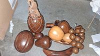 Set of wooden fruit including pineapple, round fruits, grapes on a table