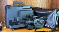 Bauer T 502 Super 8 film projector and Bauer S 209 XL Super 8 movie camera with protective cover on wooden surface.