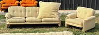 Three-seat sofa and matching armchair on grass in front of black wall