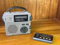 Front and side view showing Grundig FR-200 AM/FM/SW radio with tuning dials, speaker grille, and black handle next to black Seiko guitar tuner.