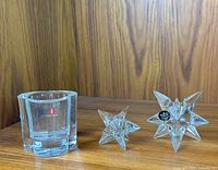 Three candle holders displayed on wood surface: two Rosenthal spike crystal star candle holders (one large, one small) and one Iittala clover-shaped glass candle holder with label visible