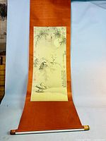 Full view of the hanging scroll showing the artwork mounted on dark goldenrod fabric with bamboo and rock at the bottom portion of the print.