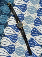 Photo showing full length of vintage Gucci ladies quartz watch with black textured leather band and gold-tone round case.