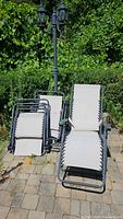 Four folding mesh sling chaise lounge chairs on patio, two open two folded