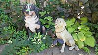 Both dog statues among garden plants