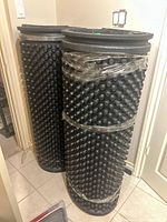 Two rolled black studded rubber mats