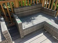 Front view of grey vinyl wicker loveseat on deck