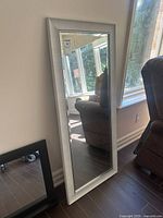 Full view of framed mirror leaning against wall