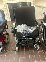 Front view of wheelchair showing seat, wheels, joystick