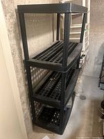 Front view of black plastic 4-tier shelving unit