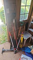 Group shot of all long-handle tools, pump, level, scoop and table in shed