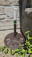 Full view of metal umbrella stand showing base design and pole