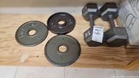 Two Steelflex 5 lb plates, one 2.5 lb plate, pair 25 lb dumbbells on shelf