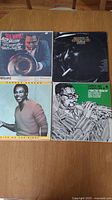 Four jazz vinyl LP records on table showing front cover art: Dizzy Gillespie New Wave!, Thelonious Monk Greatest Hits, George Benson Give Me The Night, and Capitol Jazz Classics Strictly Bebop.