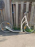 Side view of white adult kick scooter showing frame, wheels, and handlebars.