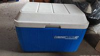 Closed view of blue and white Coleman PolyLite 40 cooler with visible brand name on front.