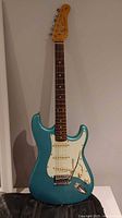 Front view of turquoise guitar showing body shape, pickups, pickguard and bridge