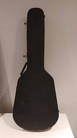 Closed black hard guitar case with handle and metal latches.