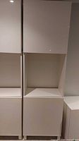 Front view of white IKEA BESTA cabinet with closed two doors and open shelf in middle section.