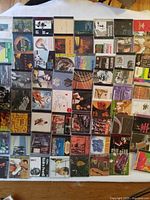 Photo showing a large assortment of Brazilian instrumental music CDs laid out in a grid pattern, approximately 65 in total