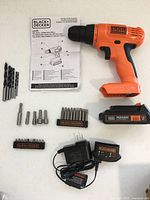 All components laid out: drill, manual, 6 drill bits, bit sets, battery, charger