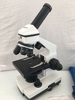 Microscope front angle showing eyepiece, objectives, stage and focusing knobs