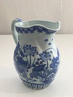 Front view of pitcher showing floral design and scalloped rim