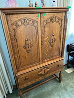 Front view of closed cabinet showing carved twin doors and lower drawer