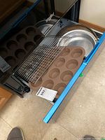Drawer containing brown silicone muffin pan, metal cooling rack, round cake pans