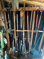 Overall view of gardening tools hanging and leaning on shed wall