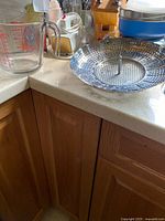 Close-up of Fire-King measuring cup and stainless steamer basket