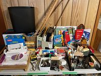 Overall view of assortment on two tables including wastebasket, paper reams, yardsticks, office sundries