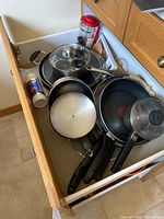 Drawer showing assorted non-stick pans, skillet, egg poacher, French press, grater, trivet