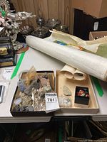 Tray holding various rough and polished rocks beside rolled maps